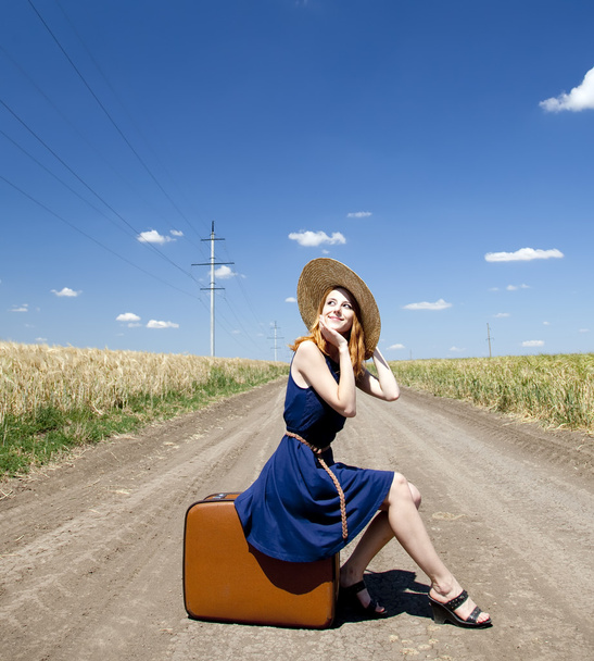 Lonely girl with suitcase at country road. - Foto, afbeelding