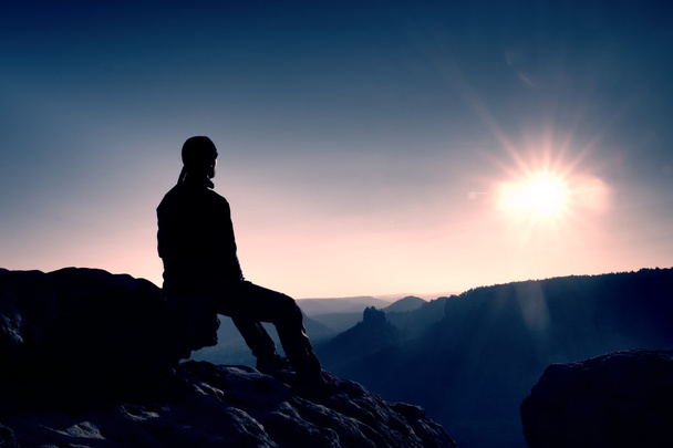 観光は、休息を取る。ハンサムな若い男岩の上に座っていると霧のロッキー山脈に景色を楽しみながら. - 写真・画像