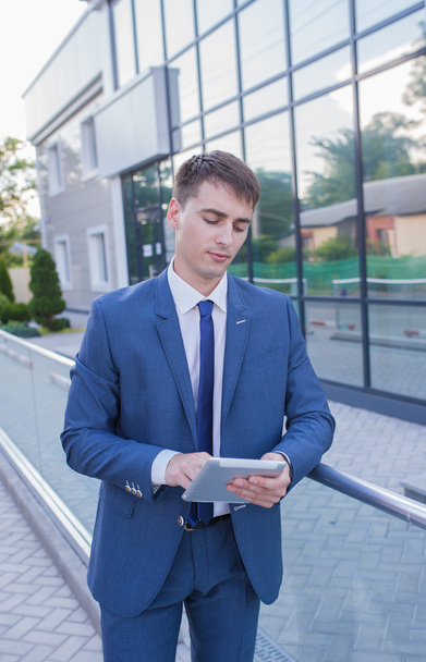 Uomo d'affari di successo in piedi in strada con un computer portatile in mano
 - Foto, immagini