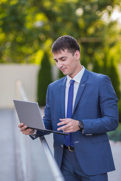 Successful businessman standing in the street holding a laptop - Photo, Image