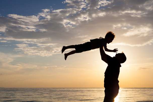 Отец и сын играют на пляже на закате
. - Фото, изображение