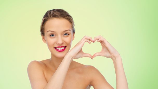 smiling young woman showing heart shape hand sign - Foto, Imagem
