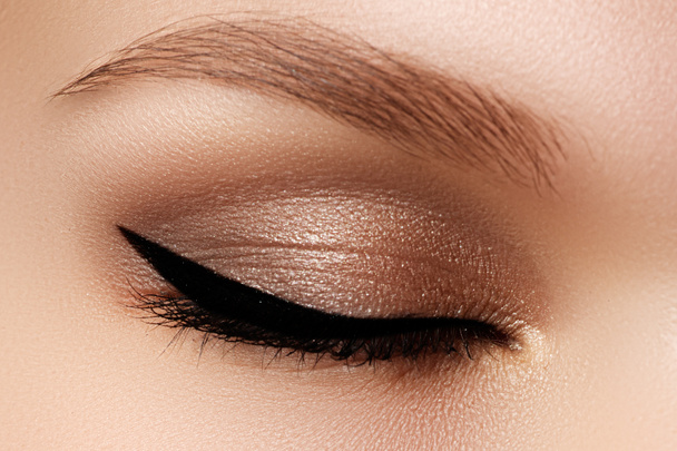 Cosmetics & make-up. Beautiful female eye with sexy black liner makeup. Fashion big arrow shape on woman's eyelid. Chic evening make-up - Zdjęcie, obraz