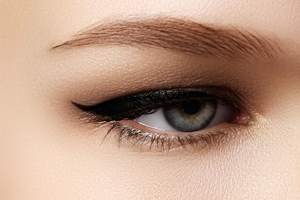 Cosmetics & make-up. Beautiful female eye with sexy black liner makeup. Fashion big arrow shape on woman's eyelid. Chic evening make-up - Photo, Image