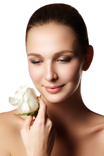 Pretty face of beautiful young woman with rose on hands - white background. Beauty face of young woman with flower. Beauty treatment concept - Photo, Image