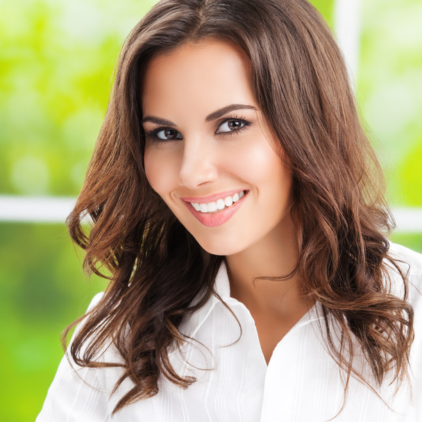 Portrait of young happy brunette businesswoman at office - Фото, изображение