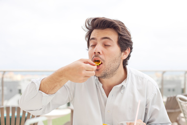 mladý muž jíst chipsy - Fotografie, Obrázek