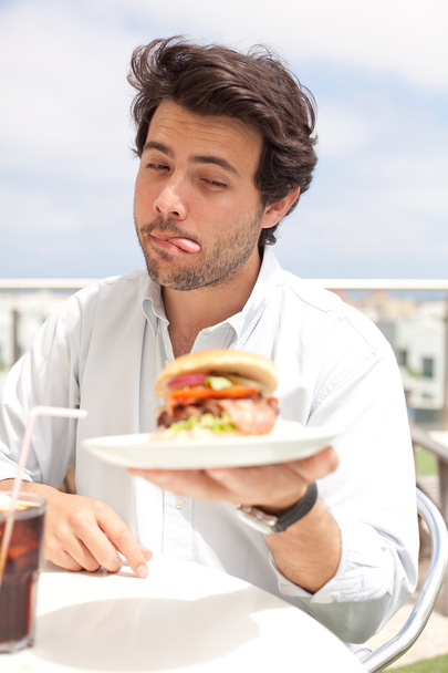 jonge man eten van een hamburger - Foto, afbeelding