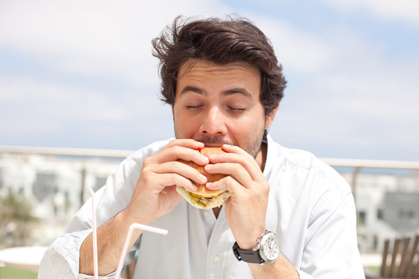 Jeune homme mangeant un hamburger
 - Photo, image