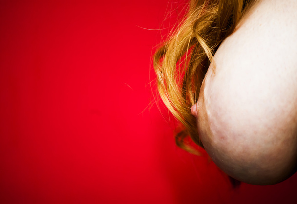 Poitrine femme nue avec ses cheveux tombant sur sa poitrine sur rouge
 - Photo, image