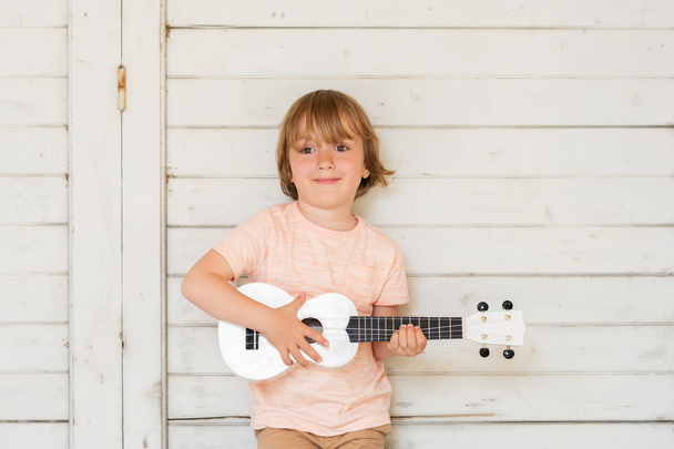 Little happy boy plays his guitar or ukulele - Fotoğraf, Görsel