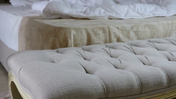 Kobieta rzuca erotyczne nocnej na puf przed Niezasłane łóżka w sypialni - Materiał filmowy, wideo