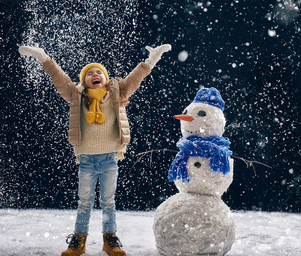 girl plaing with a snowman - Photo, image