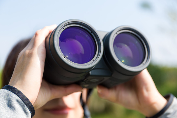 woman looking through binoculars at outdoors - Foto, afbeelding