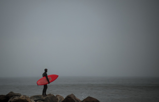 Surfer staande op de rots jetti - Foto, afbeelding