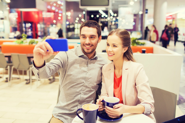 happy couple with smartphone taking selfie in mall - Foto, afbeelding