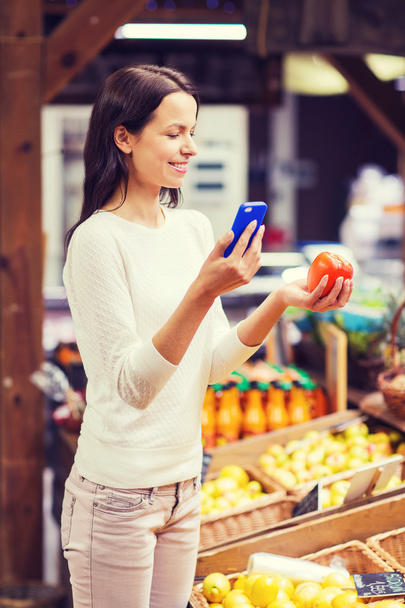 happy woman with smartphone and tomato in market - Photo, Image