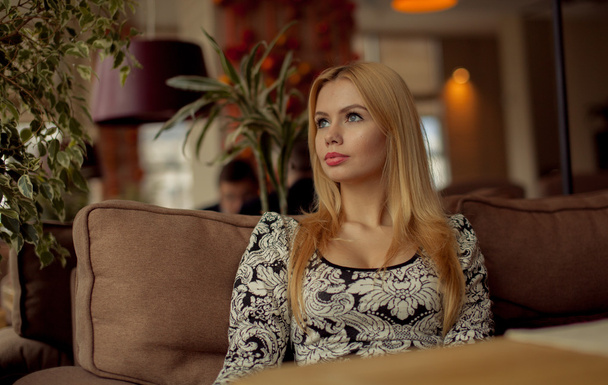 Portrait of a cute blonde smiling woman sitting in a cafe - Foto, Bild
