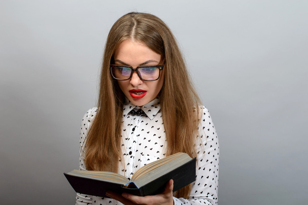 Portrait of attractive young woman in glasses reading book - Fotó, kép