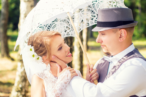 Happy bride and groom with umbrella in a forest - Photo, Image
