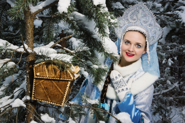 Snegurochka (Snow Maiden) with gifts bag in the winter forest - Photo, Image