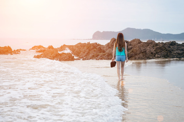 Beautiful girl walking on the beach at sunset. - Фото, изображение