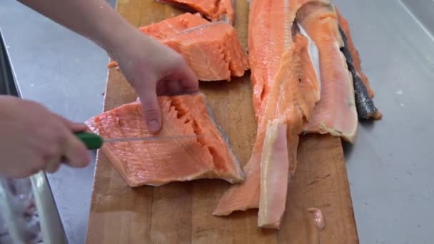 Chef cuts up the fish on the wooden board by knife in the kitchen - Footage, Video