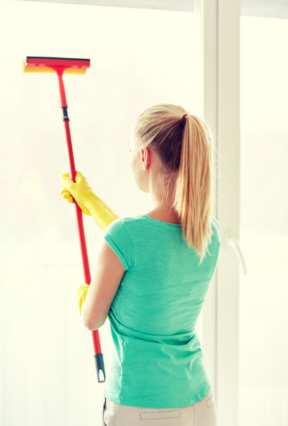 happy woman in gloves cleaning window with sponge - Zdjęcie, obraz