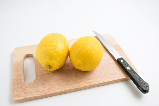 新鮮なレモンとまな板の分離の背景にナイフ - 写真・画像