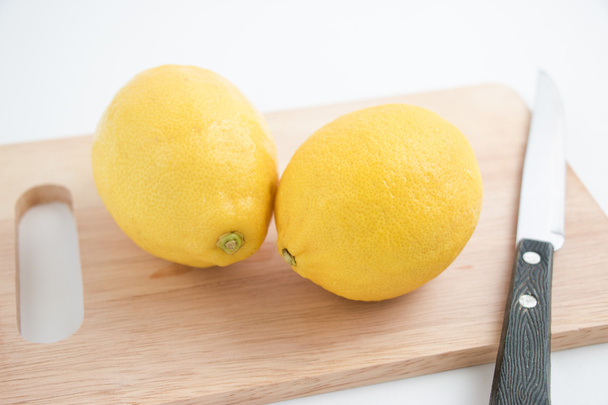 frische Zitrone und Messer auf dem Schneideblock, isolierter Hintergrund - Foto, Bild