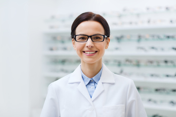woman optician in glasses and coat at optics store - Fotó, kép