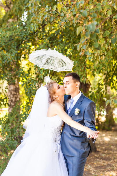 Pareja casada sosteniendo paraguas blanco
 - Foto, imagen