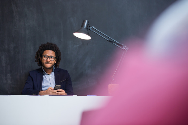 Portrait of happy smart black businessman sitting at desk in off - Фото, изображение