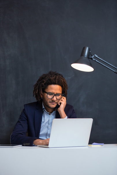 Portrait of happy smart black businessman sitting at desk in off - Foto, immagini