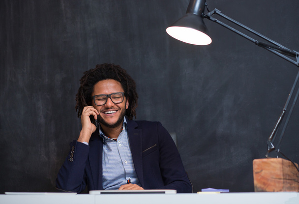 Portrait of happy smart black businessman sitting at desk in off - Fotó, kép