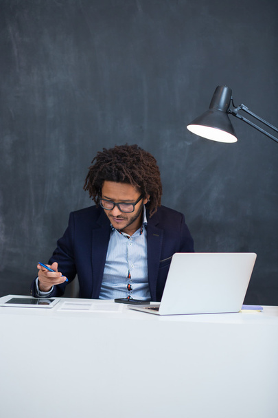 Portrait of happy smart black businessman sitting at desk in off - Foto, Imagen