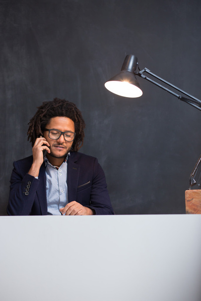 Portrait of happy smart black businessman sitting at desk in off - Фото, зображення
