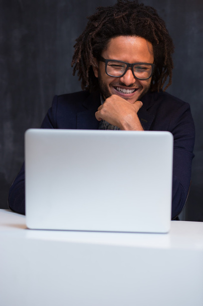 Portrait of happy smart black businessman sitting at desk in off - Foto, Bild