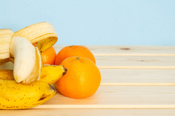Банани, мандарини на дерев'яному столі
 - Фото, зображення