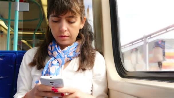 Жінка користується розумним телефоном під час подорожі поїздом у Лондоні. - Кадри, відео