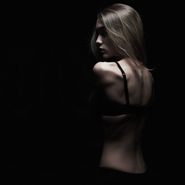 tristeza mujer joven con la espalda desnuda sobre fondo negro. oscuro monocromo retrato de sexy cuerpo chica
 - Foto, imagen