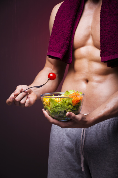 Muscular man holding a bowl of salad - Фото, зображення