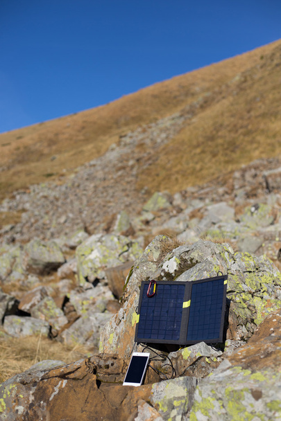 The solar panel attached to the tent. The man sitting next to mobile phone charges from the sun. - Foto, imagen