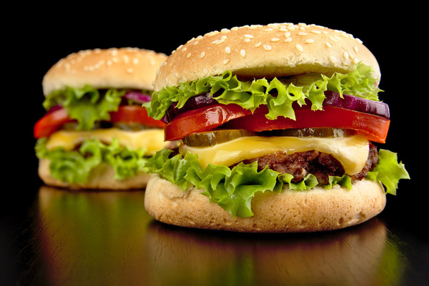 Dos hamburguesas grandes con queso aisladas sobre fondo negro
 - Foto, Imagen