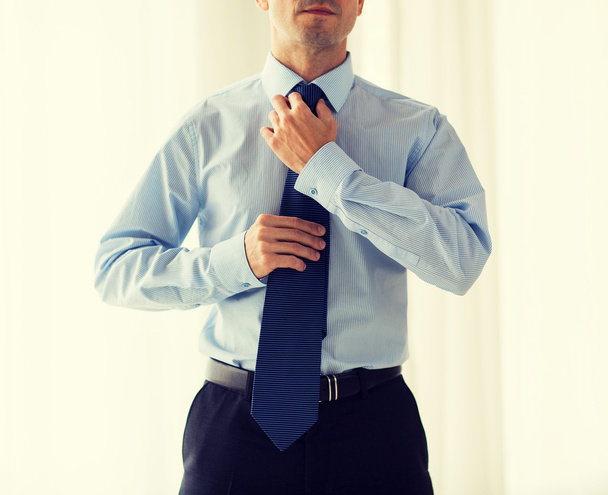 close up of man in shirt adjusting tie on neck - Fotografie, Obrázek