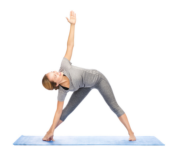 woman making yoga triangle pose on mat - Фото, зображення
