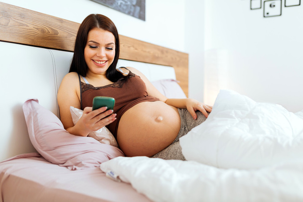 Beautiful pregnant woman using phone - 写真・画像