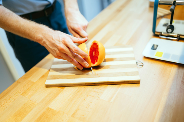 Man slicing orange in kitchen - Valokuva, kuva