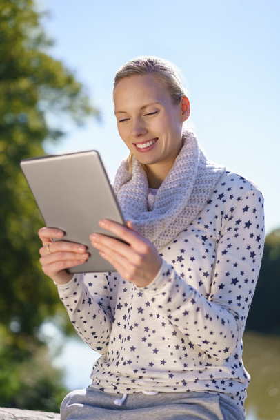 Young woman enjoying an e-book outdoors - Fotó, kép