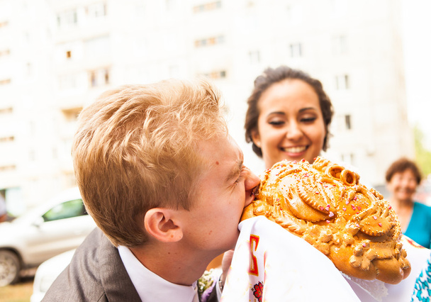 Closeup photo of bride and groom nibbling traditional loaf - Photo, Image